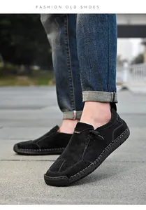 Detail van handgemaakte zwarte leren loafers met sportieve stiksels op een stenen pad