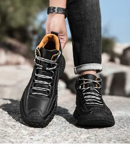 Detalle de botas de cuero negro con textura granulada, costuras amarillas y punteras de goma