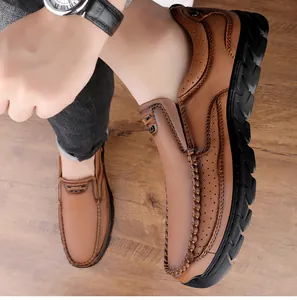 Gros plan de mocassins en cuir marron avec logo sport et coutures sur bois