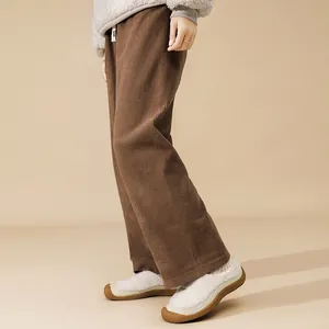 Dettaglio dei pantaloni a gamba larga in velluto a coste marroni con coulisse in vita bianca