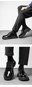 Close-up of black patent leather platform loafers featuring a chunky lug sole and laces