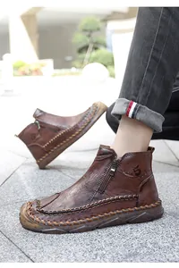 Dettaglio dello stivaletto in pelle marrone con zip laterale e cuciture intrecciate