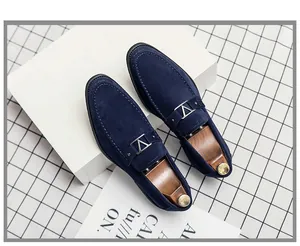 Detalle de mocasines de ante azul con hebilla en V plateada y hormas de madera de alta calidad