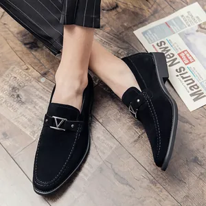 Mocasines de ante negro para hombre con hebilla en V de metal sobre suelo de madera
