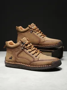 Detail der handgenähten braunen Lederstiefel mit Metallösen und Seitenlogo