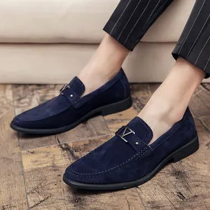 Mocasines de ante azul marino para hombre con hebilla metálica sobre suelo madera