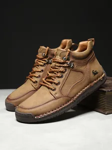 Nahaufnahme brauner Lederstiefel mit Gummisohle und handgefertigten Nähten im Detail