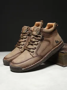 Makroaufnahme brauner Lederstiefel mit dicken Schnürsenkeln und Gummisohlen-Gravur