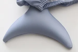 Dettaglio del costume da bagno neonato con design a coda di pesce azzurro e tessuto elastico