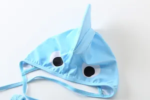 Dettaglio di una cuffia da nuoto neonato azzurra con pinna di squalo e occhi cartoon