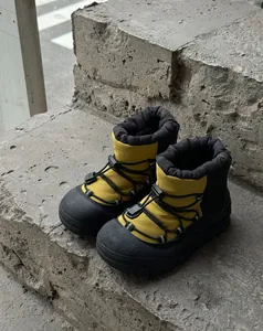Detail of waterproof winter snow boots featuring a warm yellow nylon upper and rubber sole