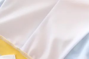 Macro detail van witte mesh stof met gele bies en nauwkeurige stiksels van het zwempak