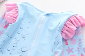 Detail eines langärmeligen Mädchen-Badeanzugs mit rosa Rüschen und Meeresmotiven
