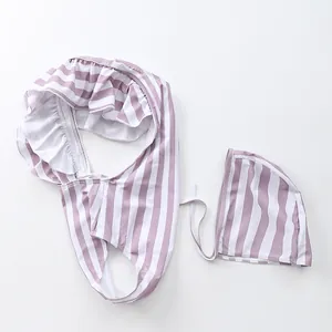 Close-up of lilac and white striped baby swimsuit set with ruffle detail and matching swim cap