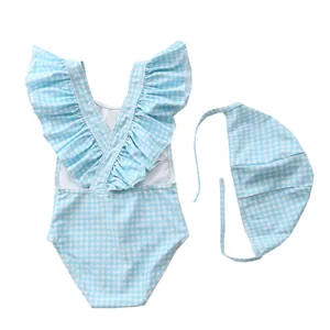 Detail of baby girl striped swimsuit featuring ruffled shoulder straps and matching swim cap