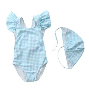 Flat lay of light blue gingham toddler swimsuit set with ruffled shoulders and matching cap