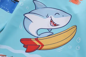 Gros plan détaillé des motifs de requin et crabe sur le tissu bleu du maillot enfant