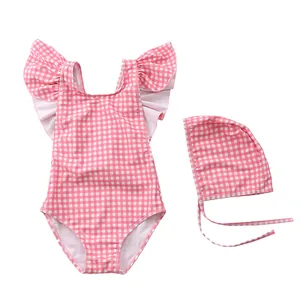 Flat lay of pink striped toddler swimsuit with ruffle shoulders and matching swim cap