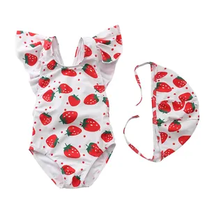 Detail of girls' ruffled swimsuit and cap set featuring red strawberry and polka dot patterns