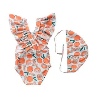Detailed view of baby girl swimwear with orange fruit patterns and ruffled shoulders