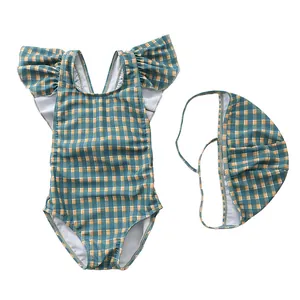 Detail of baby girl's plaid swimsuit with ruffle shoulders and matching swim cap