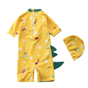 Detailed view of yellow kids' swimsuit featuring cartoon notes and dinosaur fin details