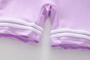 Detailansicht eines lila Badeanzugs für Mädchen mit weißen Streifen und Saumdetails
