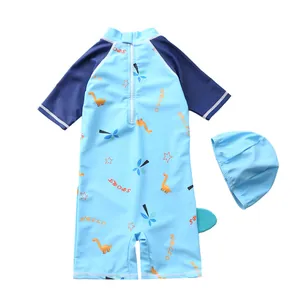 Detail of blue boys' one-piece swimsuit with cartoon dinosaur print and matching swim cap