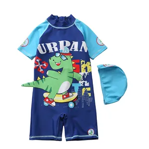 Detail of boys' one-piece swimsuit with dinosaur skate print and matching swim cap