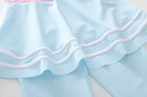 Dettaglio del costume da bagno bambina azzurro con bordo rosa e linee bianche ondulate