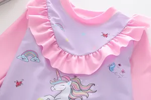Dettaglio dello scollo a volant rosa e motivo unicorno sul costume da bagno bimba