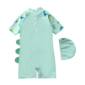 Flat lay of mint green dinosaur kids swimsuit set with matching swimming cap