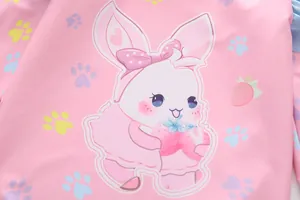 Macro detail of cute cartoon bunny and strawberry print on pink kids swimsuit fabric