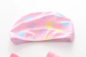 Close-up of pink kids swimming cap with blue clouds and colorful paw prints