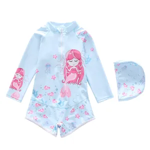 Flat lay of long-sleeved kids swimsuit set with mermaid prints and a matching swim cap