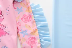 Detail of girls' pink swimsuit with ocean mermaid print and light blue ruffle accents