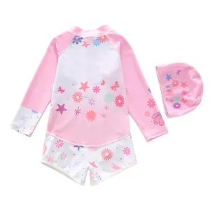 Detailed flat lay of long sleeve girls swimsuit set with floral patterns and swim cap