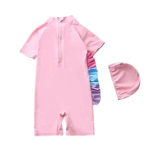 Détail d'un maillot de bain rose pour enfant avec volants arc-en-ciel et bonnet assorti