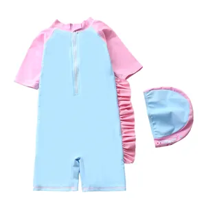 Détail d'un maillot de bain fille avec bonnet licorne et volants roses sur bleu