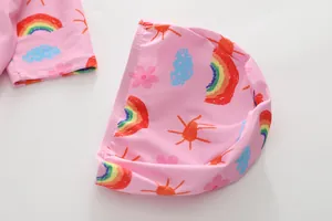 Détail du tissu de maillot de bain rose pour enfants avec motifs arc-en-ciel et soleil
