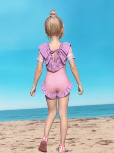 Détail d'un maillot de bain fille avec volants violets et noeud sur une plage ensoleillée