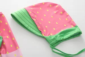 Dettaglio del tessuto rosa con motivo a fragola, bordo verde e cuciture piatte resistenti