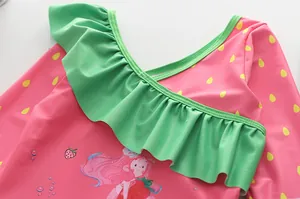 Dettaglio del costume da bagno rosa per bambine con volant verdi e stampa a fragola