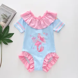 Détail d'un maillot de bain fille avec motif sirène et volants roses sur tissu bleu ciel