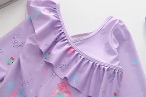 Dettaglio dello scollo a balze su costume da bagno viola con stampe a sirena