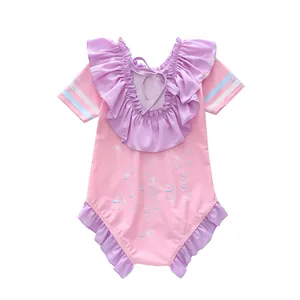 Détail du maillot de bain rose pour fille avec volants violets et nœud au dos
