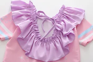 Détail du maillot de bain fille rose avec volants lavande et motifs à rayures bleues