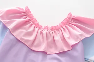 Détail de l'encolure à volants roses et du tissu violet élastique du maillot enfant