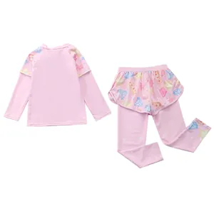 Detail of pink long-sleeve kids swimsuit featuring cartoon patterns and ruffled waist