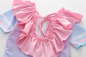 Détail du col à volants roses et du nœud à lacets sur maillot de bain violet fille